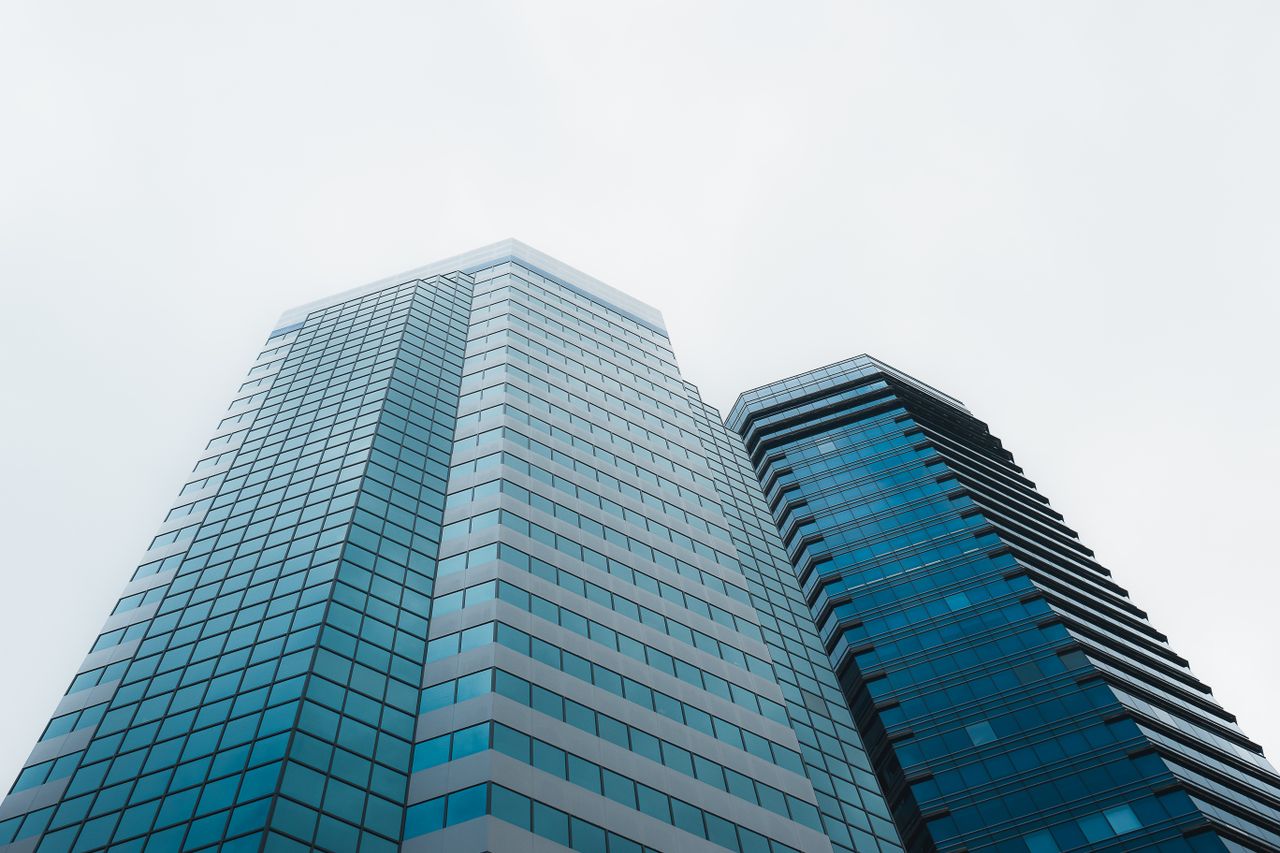 The Art of Drawing Readers In: Your attractive post title goes here Low angle view of modern skyscrapers in Hong Kong against a cloudy sky, showcasing architectural design.