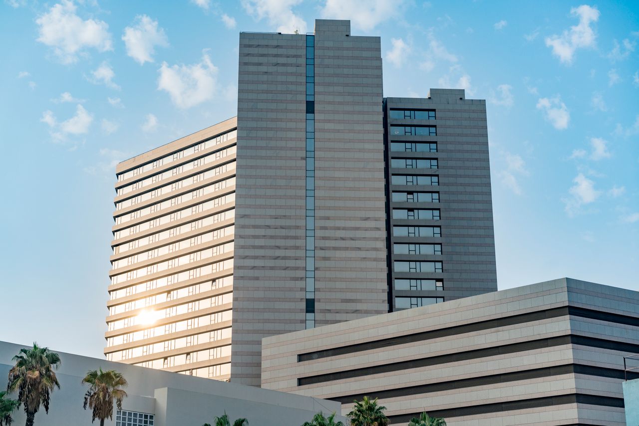 A sleek, modern skyscraper featuring a reflective glass facade under a clear blue sky.