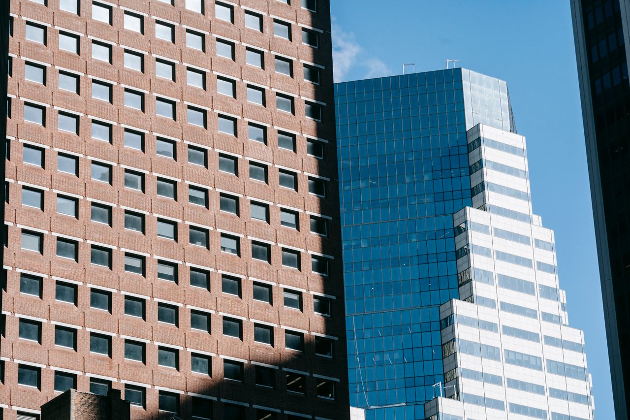 Home From below of multistory residential building located near modern skyscraper in megapolis under blue sky